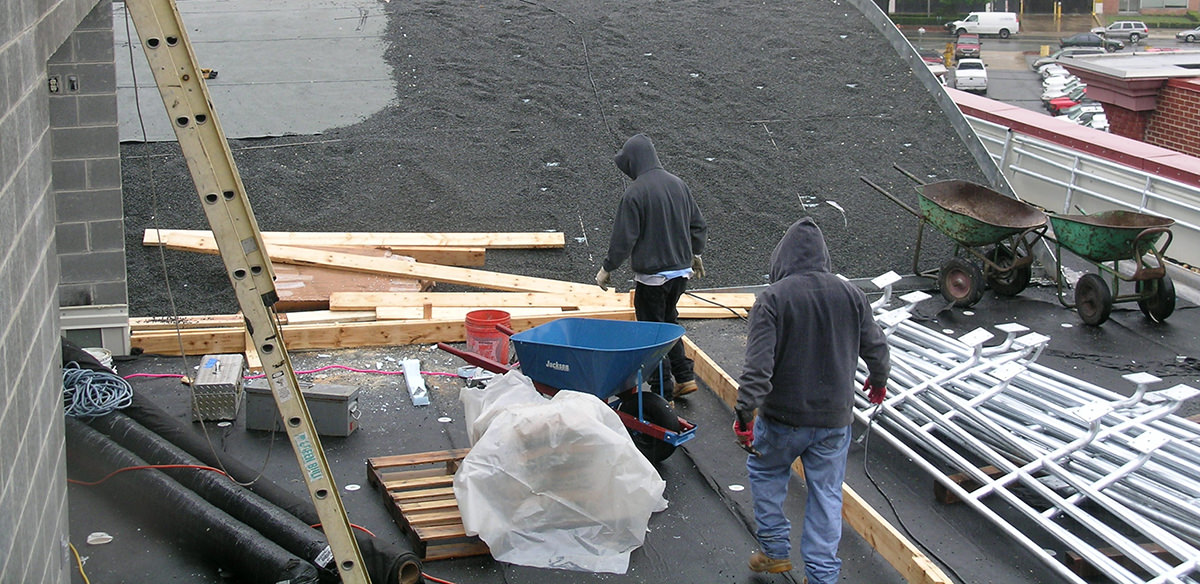 Four workers pouring soil onto a roof